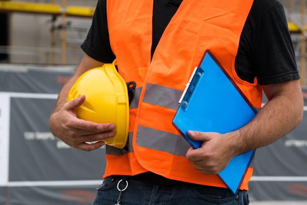 worker wearing safety vest and holding helmet