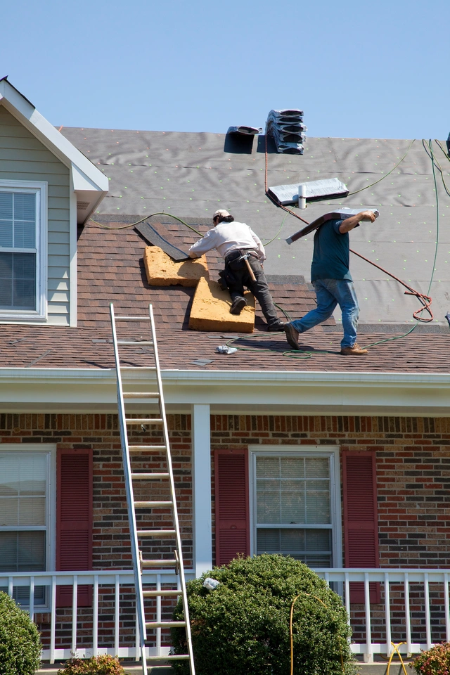construction crew replacing the brick house roof shingles