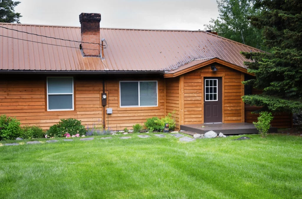 wood siding and metal roof on cabin with a front yard