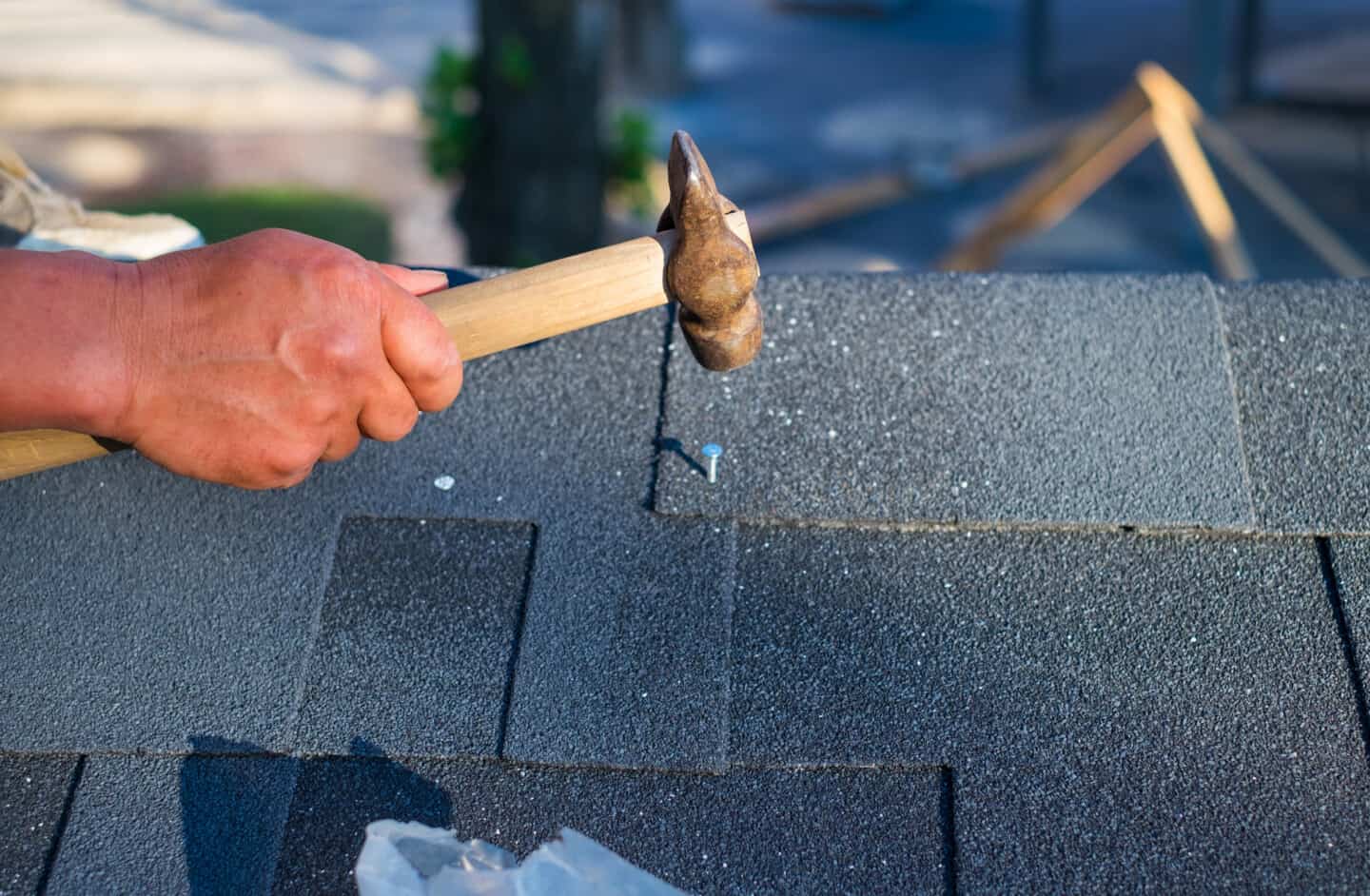 close up to worker hammering shingles