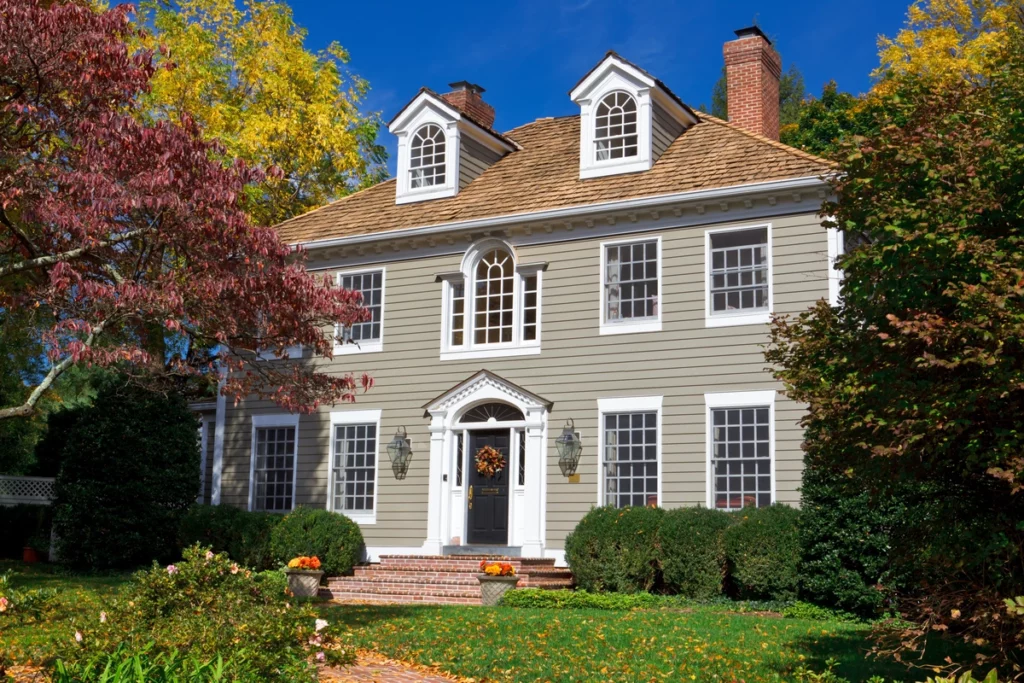 A beautiful house with tan siding, surrounded by trees