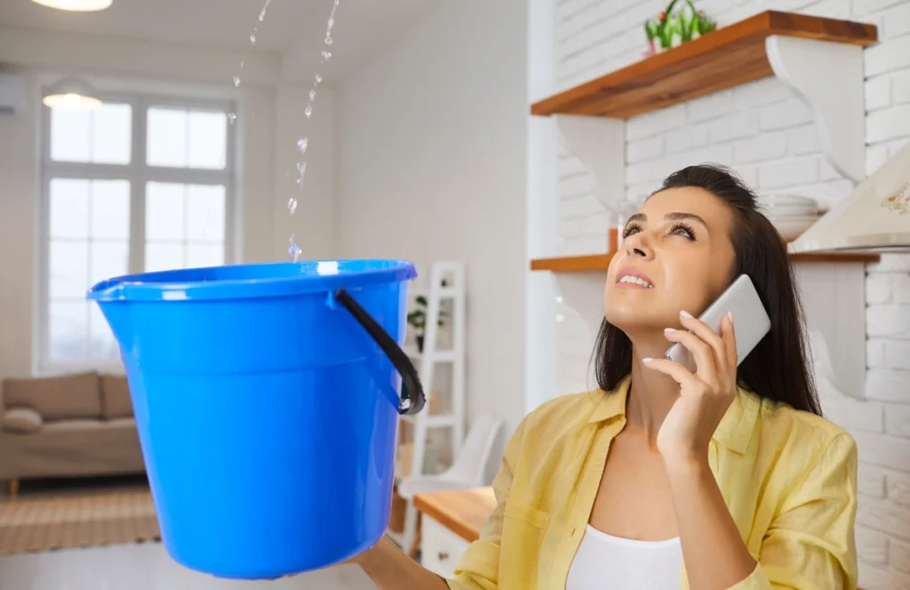 water leaking from ceiling-woman catching water from ceiling leak in a bucket