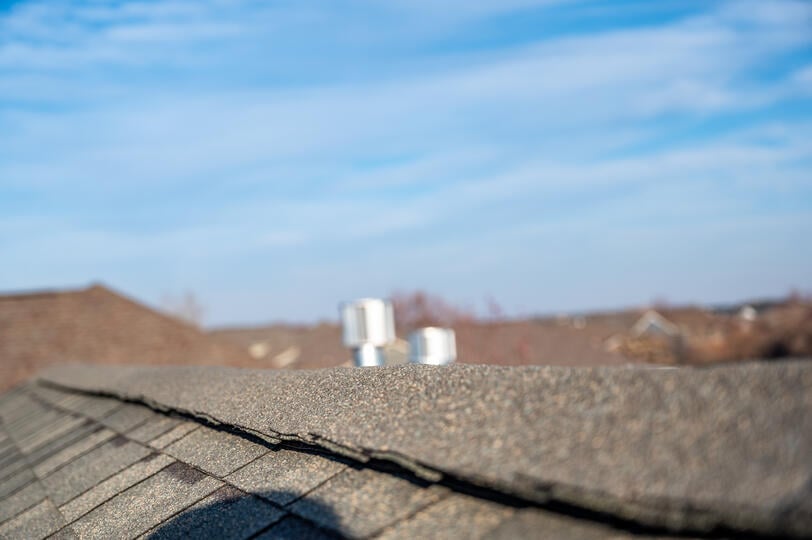 ridge cap shingles-viewing the ridge of a home with neighborhood roofs and the sky in the background