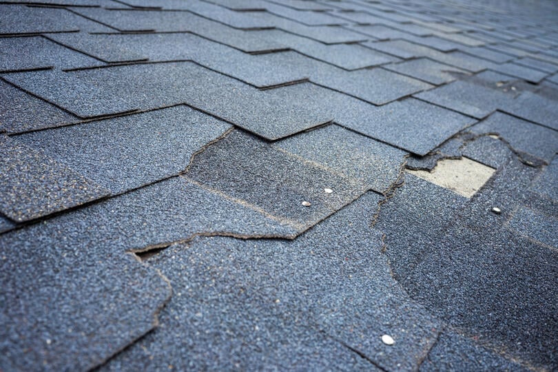 roof leak repair cost-close up of damaged shingles that need repair