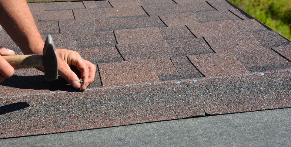 where to nail shingles-roof tech using hand held hammer to nail shingles along a chalk line