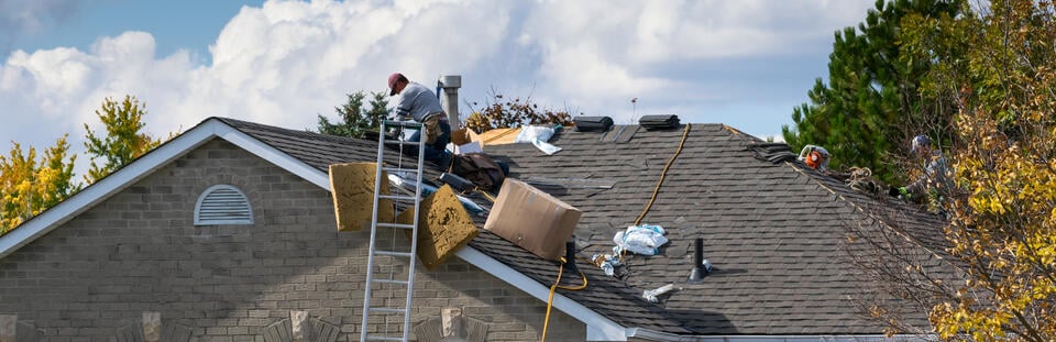 new roof installation-distant view of roofers installing new shingles on a house roof