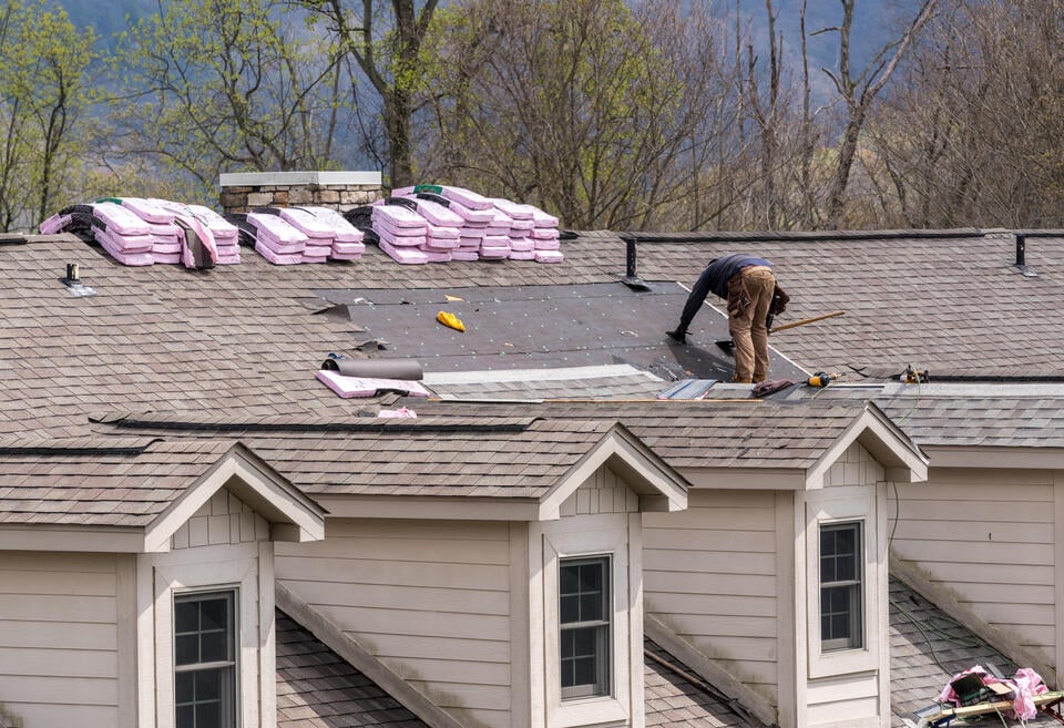 new roof installation-man standing on a roof installing new shingles on a roof