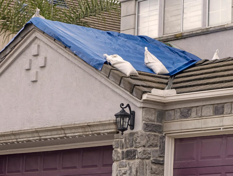 roof tarping-garage roof with blue tarp weighed down with sand bags