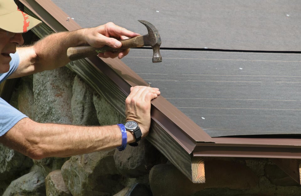 drip edge flashing-man using a hammer to install drip edge flashing on a roof