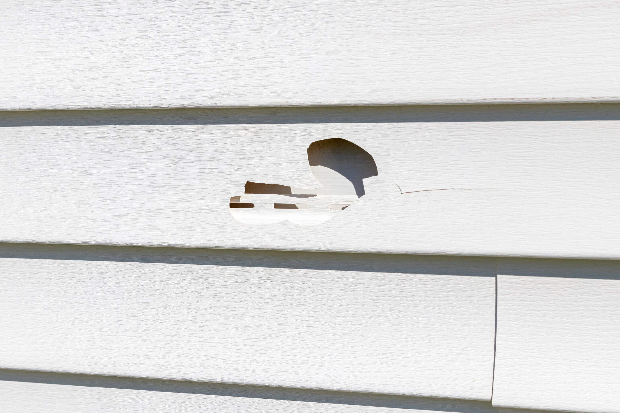 hail damage siding-close up of hail damage on white vinyl siding