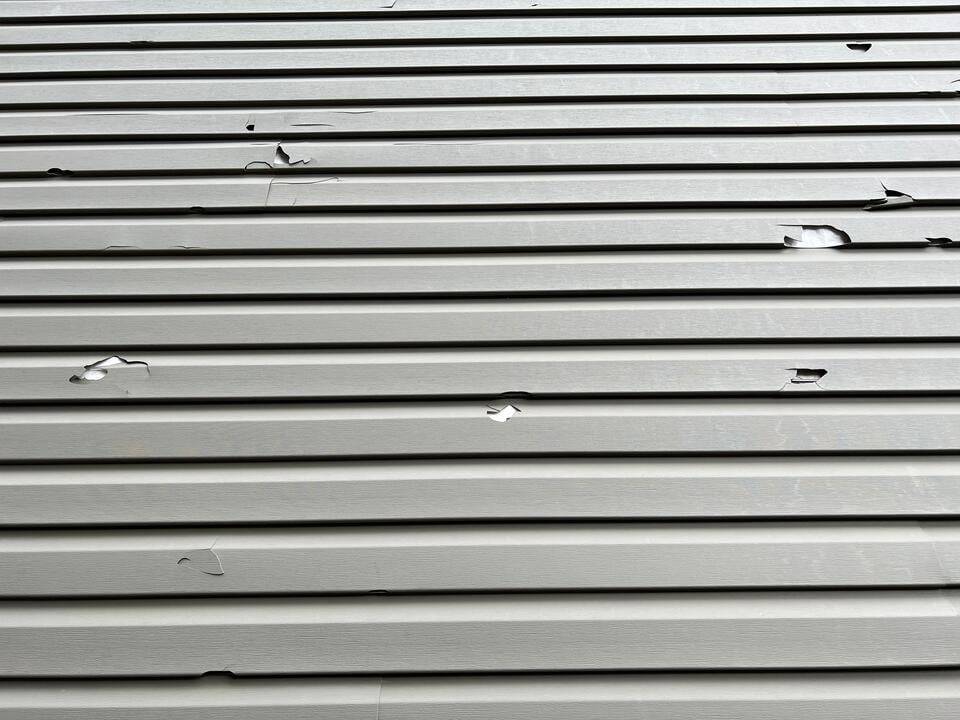 hail damage siding-close up of house siding damaged from hail