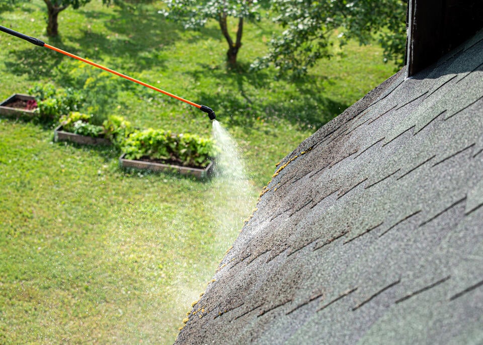 roof coatings-someone spraying a mixture onto a roof to prevent and treat moss