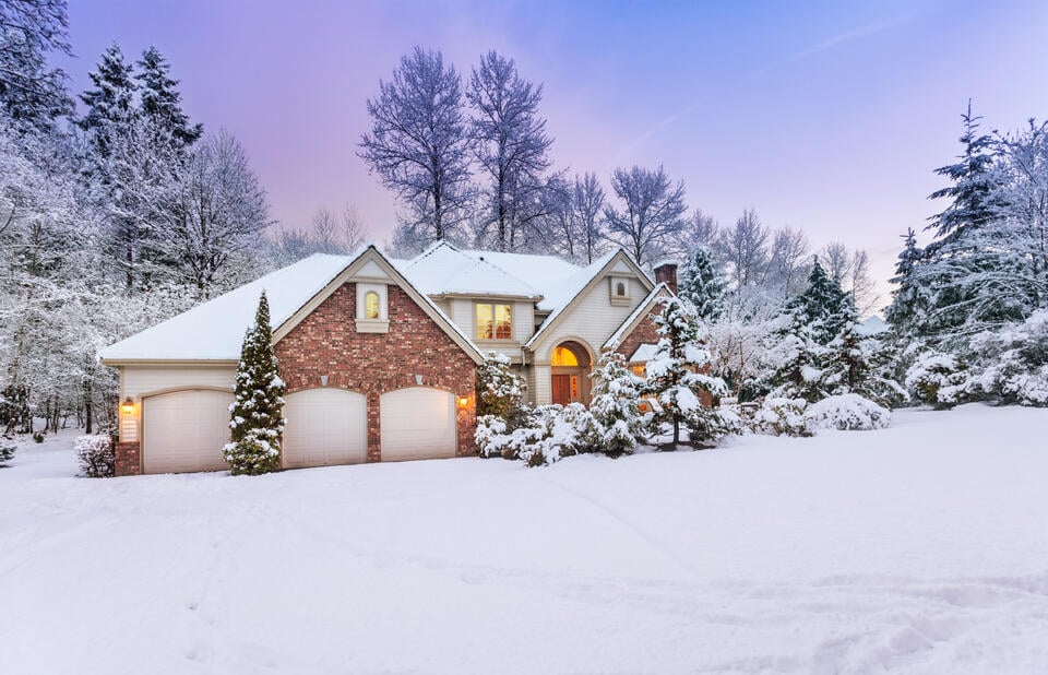 brick sided house with heavy snowfall and daylight fading in the background