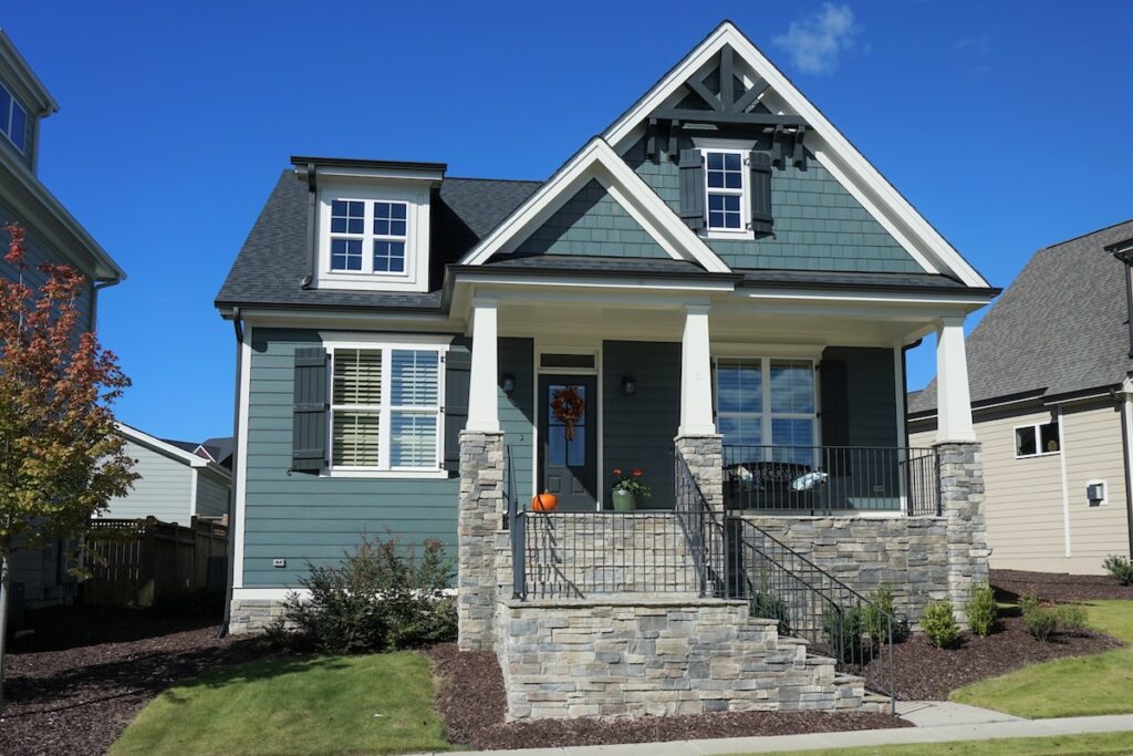 Exterior view of a two-story suburban home with a stone porch in autumn.  Built in 2017 in North Carolina.