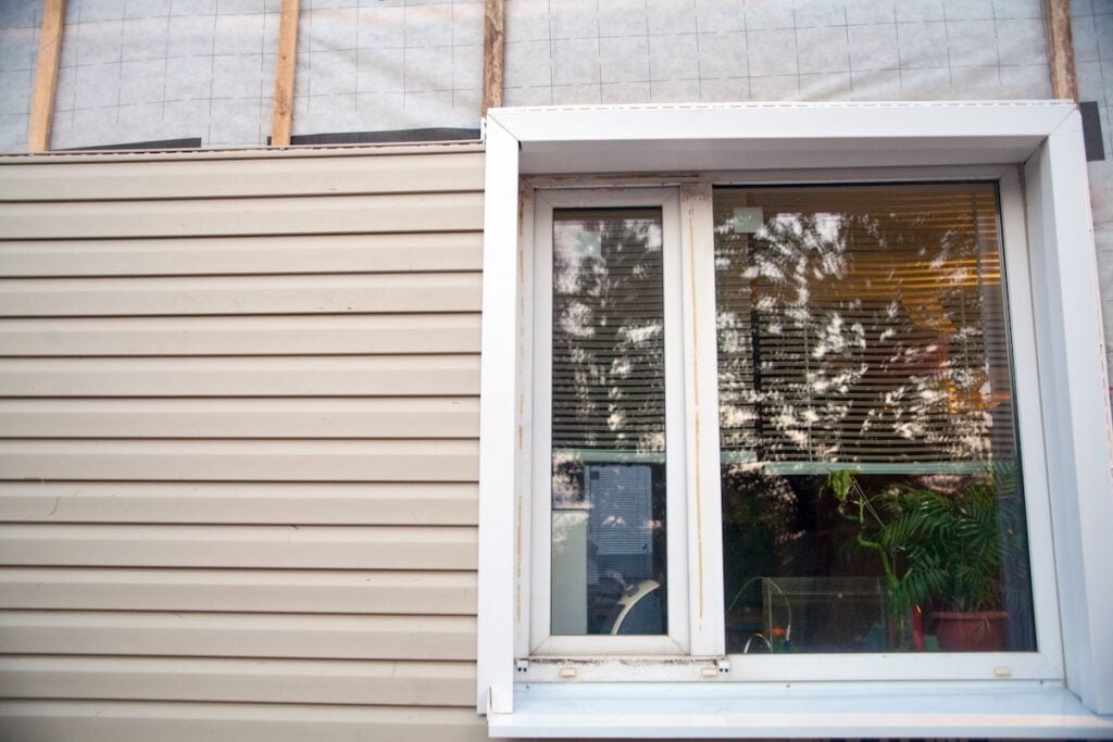 Wall covering of the frame house with panels of vinyl siding of gray color. Decorating the house with siding. The master updates the look of the old house with siding. vinyl siding that looks like wood